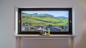 Une fenêtre donnant sur un paysage verdoyant, un radiateur en dessous et un plateau orné d’objets décoratifs.