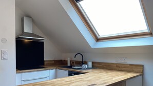 A modern kitchen with a skylight, wooden countertops, a black stove, and a sink. - Cozy Studio near Quimper Train Station – Modern & Bright (Quimper)