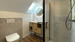A modern bathroom with a skylight, a glass-enclosed shower, and a wooden vanity. - Cozy Studio near Quimper Train Station – Modern & Bright (Quimper)