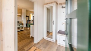 Ein Zimmer mit Holzboden, einem Spiegel, einer weißen Kommode und einem Sofa.