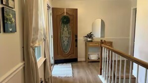 Ein Flur mit einer Holztür, einer weißen Bank und einer Treppe mit einem Holzgeländer.