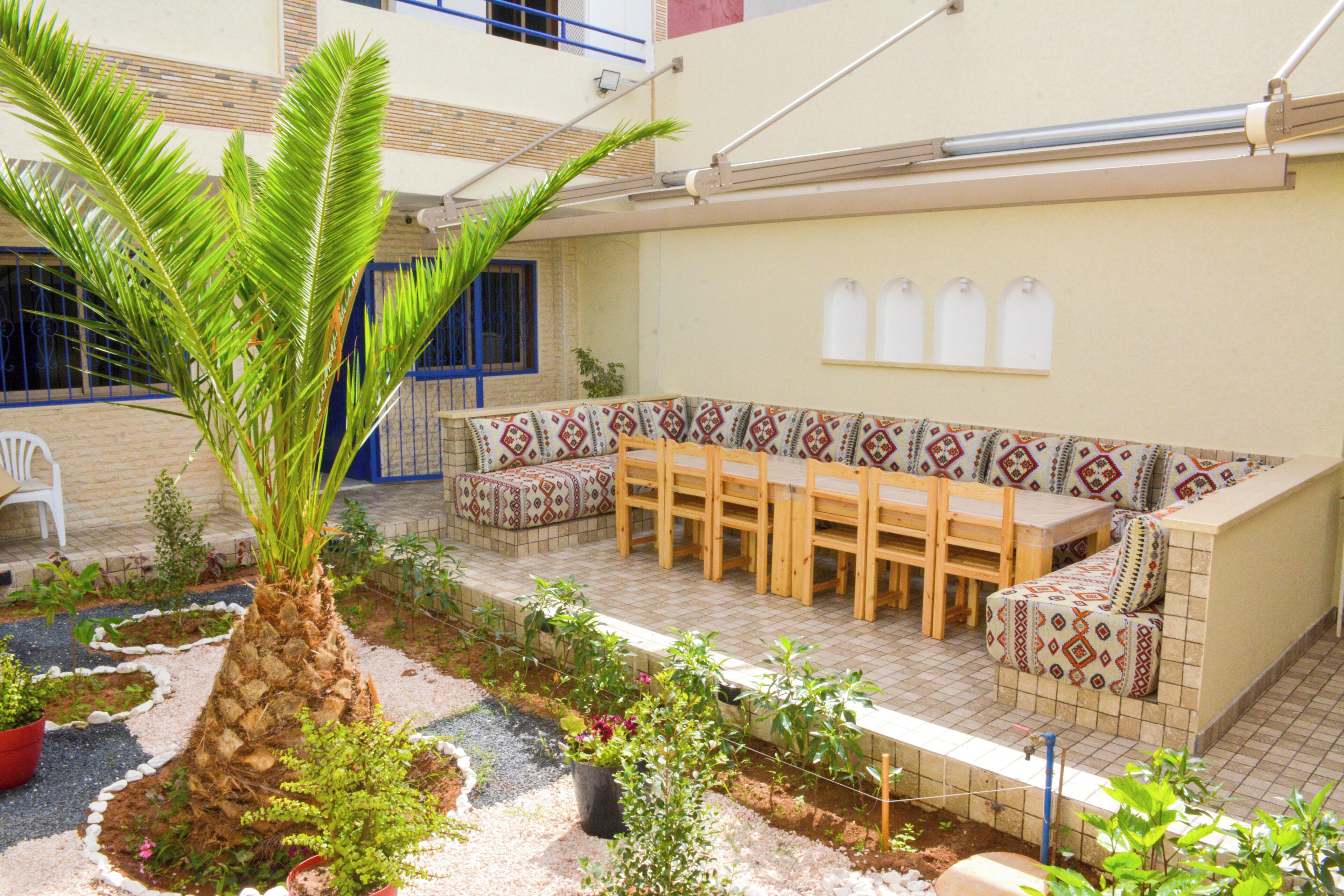 Un patio al aire libre con piso de baldosas, un banco de madera y una palmera.