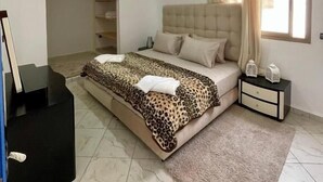 A bedroom with a bed, a nightstand, a dresser, a ceiling light, and a window with curtains. - auberge dar fayçal (Mirleft)