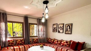 A living room with a sofa set, a round coffee table, and a chandelier. - auberge dar fayçal (Mirleft)