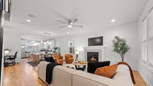A modern living room with a sofa, chairs, a fireplace, and a television. - Stylish 3BR Retreat Near OSU - Sauna & Fire pit (Columbus)