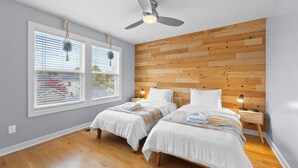 A bedroom with two beds, a ceiling fan, and a wooden wall panel. - Stylish 3BR Retreat Near OSU - Sauna & Fire pit (Columbus)