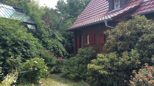 A house with a red roof, surrounded by dense greenery and a small garden. - Apartment 'Cipolla' with Private Terrace, Private Garden and Wi-Fi (Oberkirch)