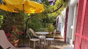 A patio with a yellow umbrella, white metal chairs, and a lounge chair. - Apartment 'Cipolla' with Private Terrace, Private Garden and Wi-Fi (Oberkirch)