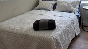 Makuuhuone, jossa on sänky, tyynyjä, peitto ja yöpöytä.