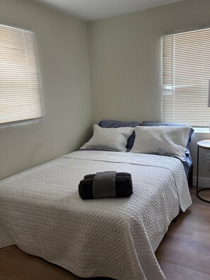 Une chambre à coucher avec un lit, des oreillers, une couverture et une table de chevet.