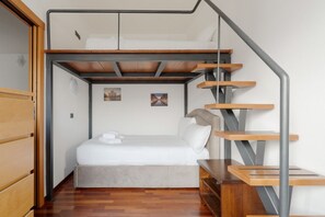 A compact room with a bunk bed, a wooden desk, and a staircase.