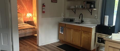 A compact kitchen with wooden cabinets, a microwave, a coffee maker, and a sink.