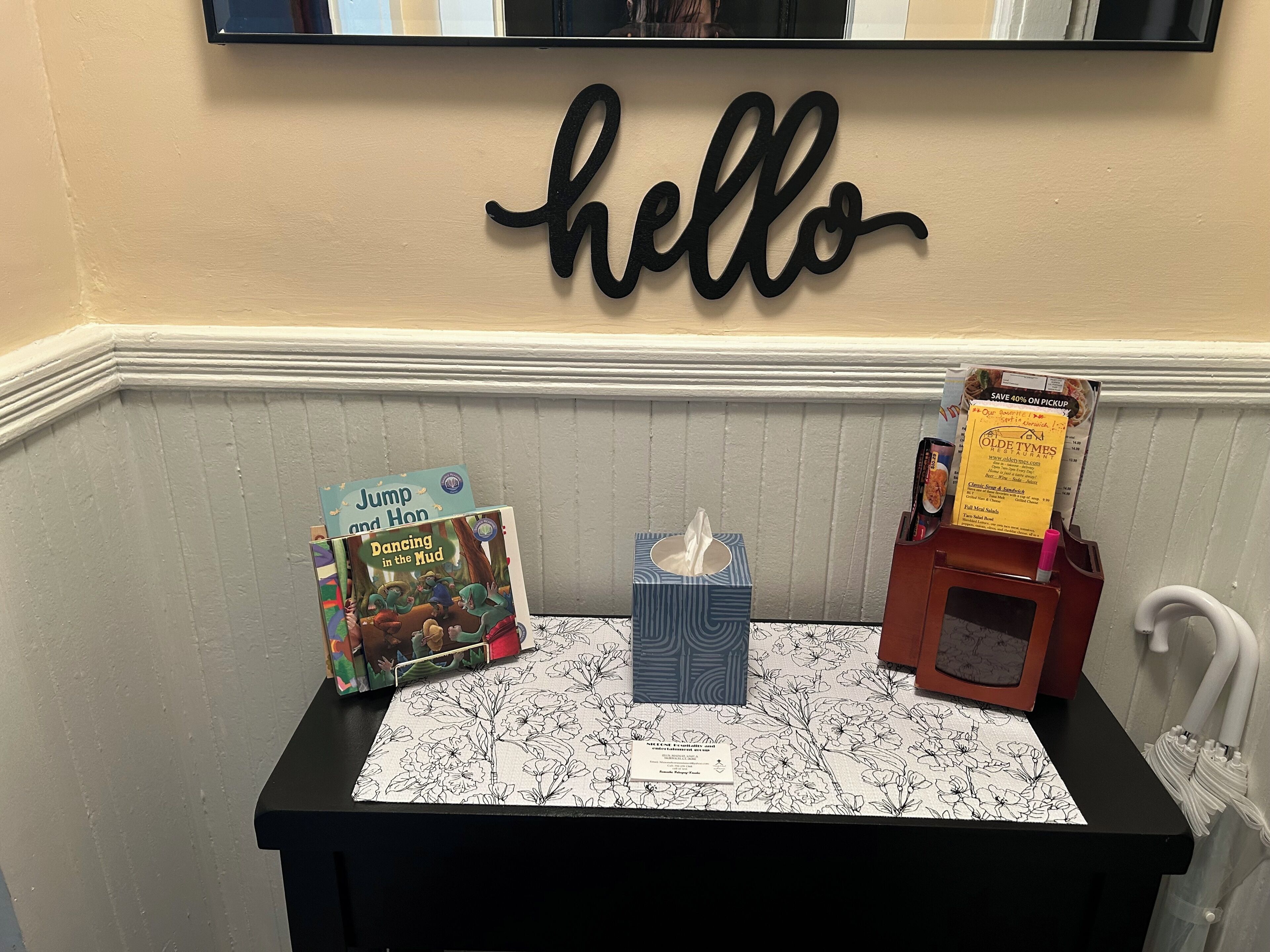 Une petite table avec des livres pour enfants, une boîte de mouchoirs et un présentoir à menus.