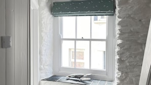 A room with a window seat, a ceiling fan, and a stone wall.