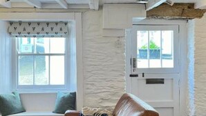 A room with a white textured wall, a window with a patterned valance, a white door, and a brown leather chair.