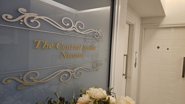 Paredes com o texto "The Central Suites Nicossia" e desenhos decorativos em espiral.