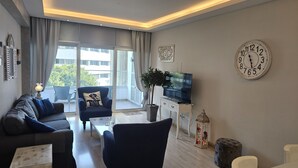 A modern living room with a sofa, armchairs, a TV, and a potted plant. - 116 NIC 302b - Stay Armonia Central Suite (Nicosia)