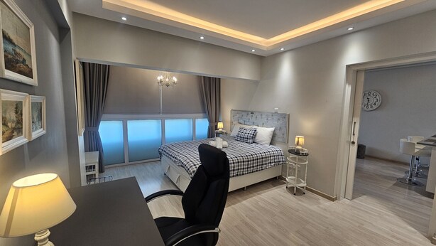 A modern hotel bedroom with a large bed, bedside tables, a desk, and a chair. - 116 NIC 302b - Stay Armonia Central Suite (Nicosia)