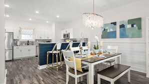 Une cuisine moderne avec des meubles blancs, un îlot central et un coin repas comprenant une table et des chaises.