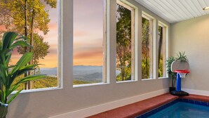 A pool area with a view of a sunset and trees, a basketball hoop, and a potted plant. - Twin Summit Resort (Sevierville)