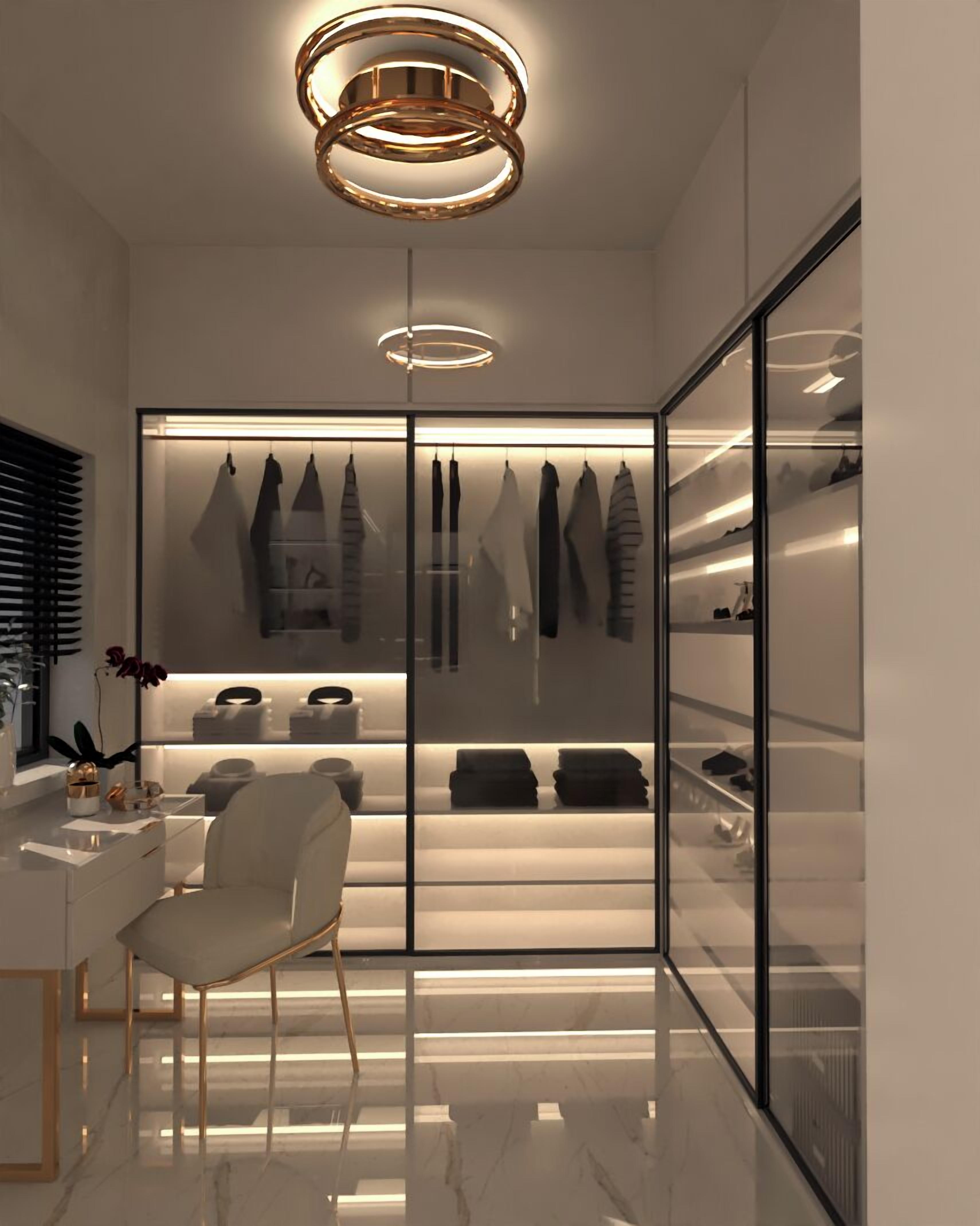 A modern walk-in closet with a glass door, a chair, and a pendant light.