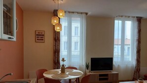 Una sala moderna con comedor, televisor y ventanas amplias.