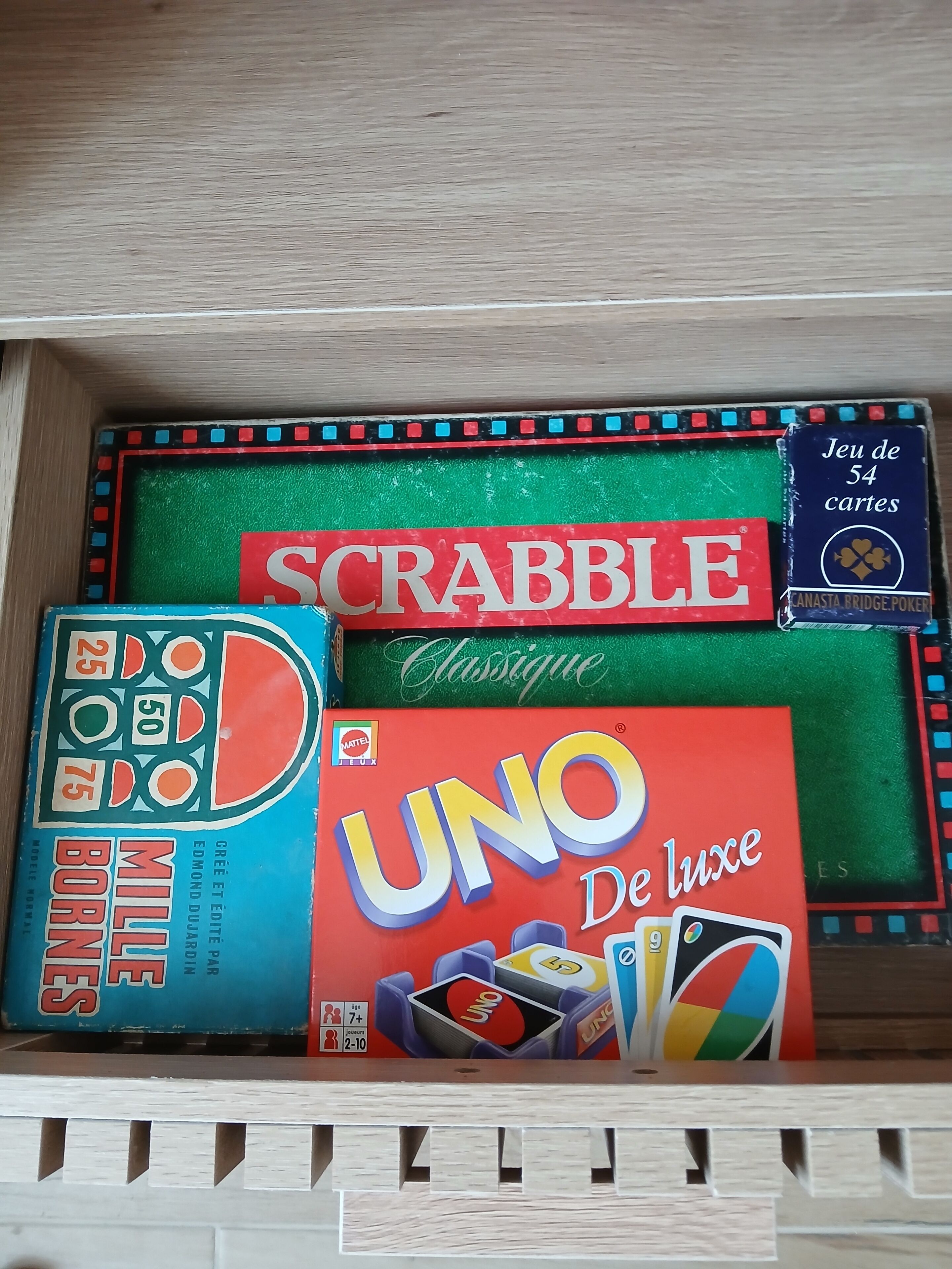 Un cajón con juegos de mesa, incluyendo Scrabble, UNO y Born Mice.