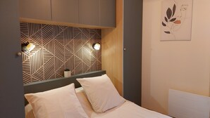 Un dormitorio con cama, dos lámparas de noche, una obra de arte en la pared y un cabecero con estampado geométrico.