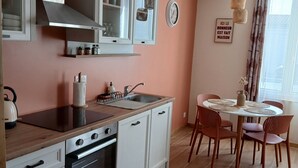 Una cocina moderna con armarios blancos, horno empotrado y comedor con mesa y sillas redondas.