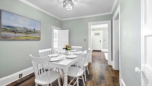 Comedor con una mesa rectangular dispuesta para seis personas, rodeada de sillas blancas.