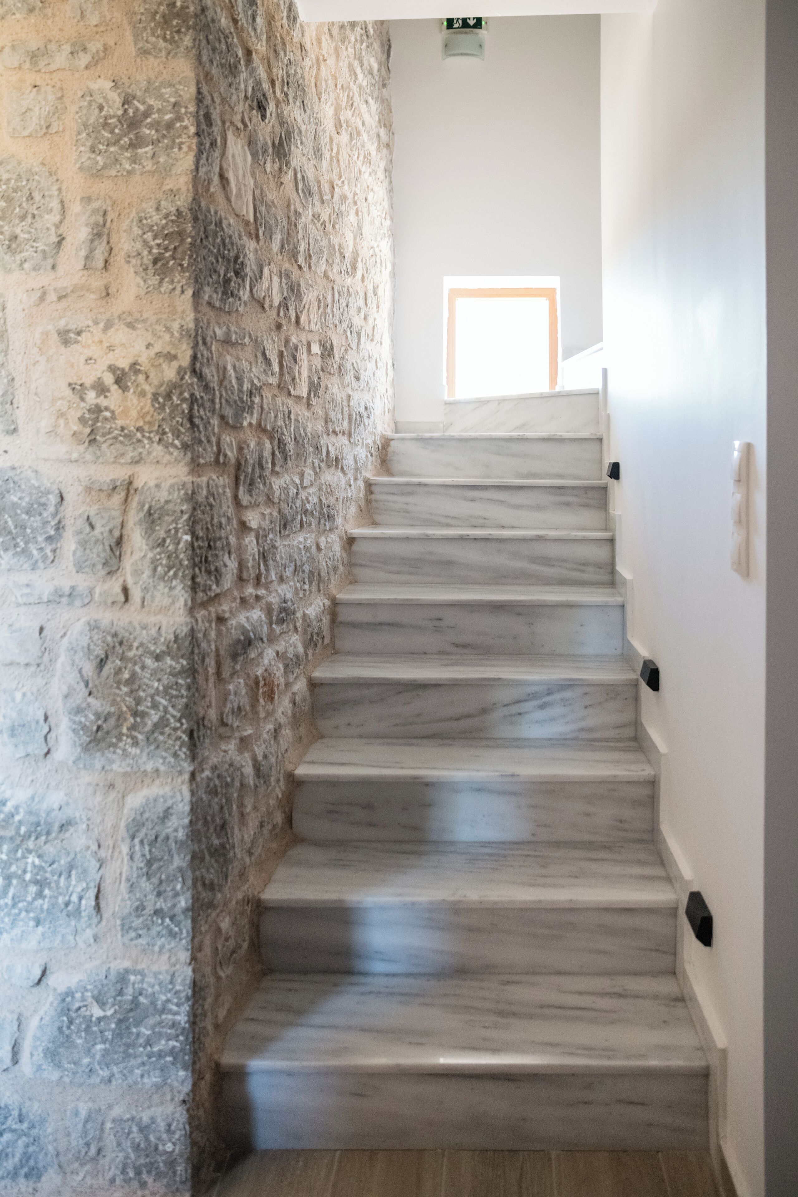 A marble staircase with a stone wall on one side.
