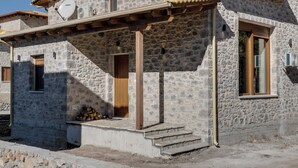 Ein Steinhaus mit einer Holztür, einer Satellitenschüssel und einer überdachten Veranda.