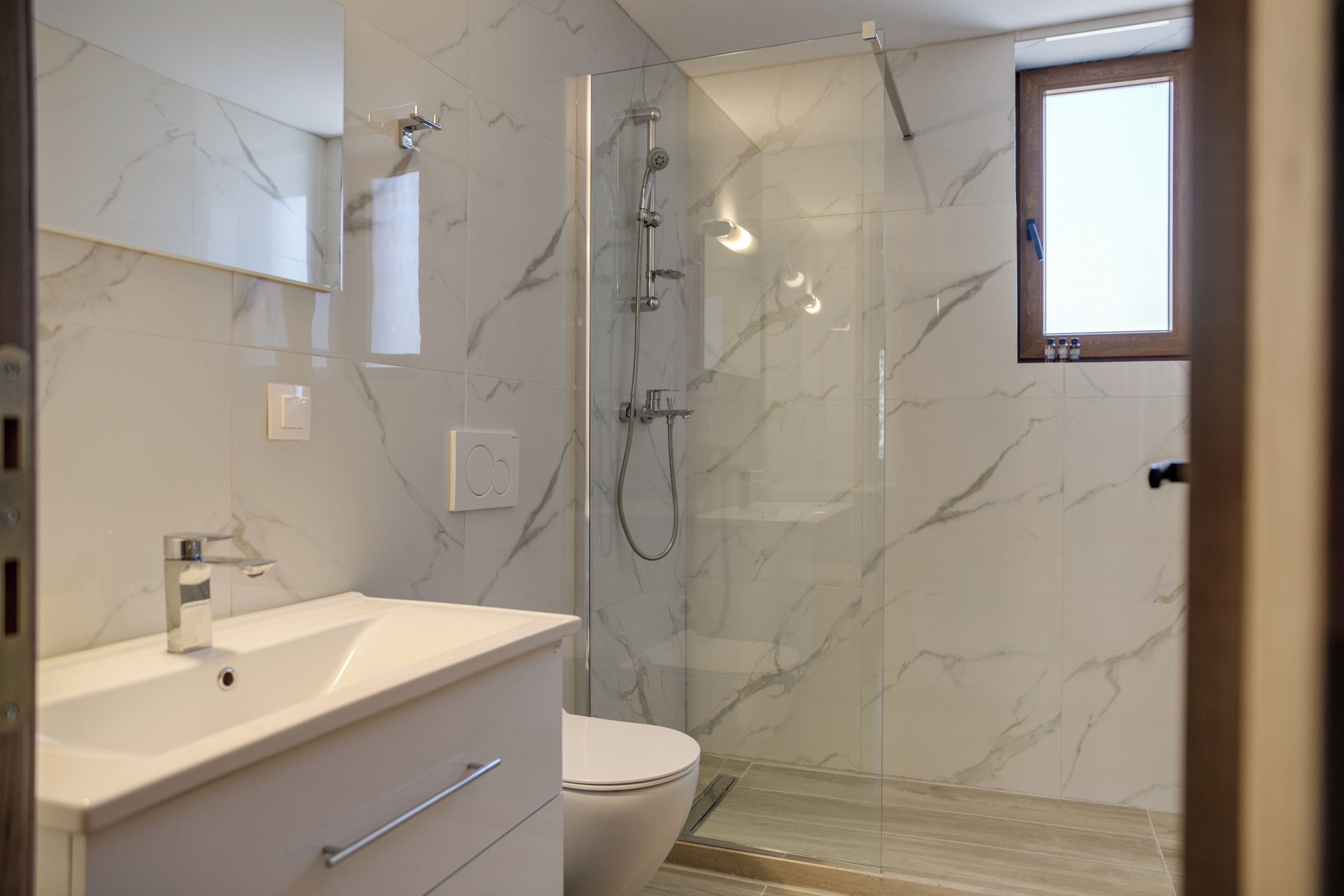 A modern bathroom with a glass-enclosed shower, a white sink, and a toilet.