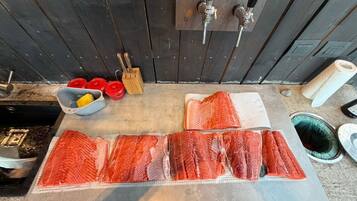 A kitchen counter with raw salmon, a knife block, and a rolling pin.