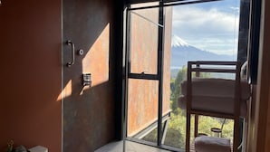 A modern room with a large sliding glass door leading to a balcony with a mountain view. - Ampe Lodge (Puerto Varas)