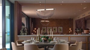 A modern dining area with a round table set for six, surrounded by six chairs. - Patamar Luxury Condo - Includes Chef, Maid & Premier Access (Punta Mita)