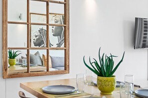 A dining area with a wooden table, chairs, a yellow plant, and a framed artwork on the wall. - The Quadrant 406 (Cape Town)