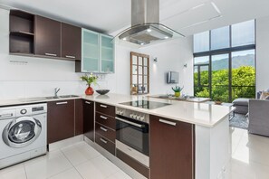 A modern kitchen with a built-in washer, a large island, and a view of greenery outside.