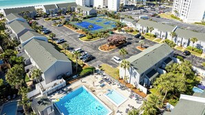 Vue aérienne d’un hôtel comprenant plusieurs bâtiments, un parking, un court de tennis et une piscine.