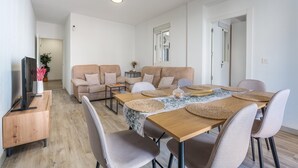 Un salon moderne comprenant un coin repas, un ensemble de canapés, un téléviseur et un meuble en bois.