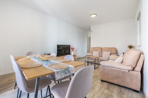Uma sala de estar moderna com uma mesa de jantar, sofá e televisão.