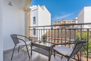 A balcony with two wicker chairs, a glass table, and a potted plant. - Apartment 'Bright  in Maracena' with Private Terrace, Wi-Fi and Air Conditioning (Granada)