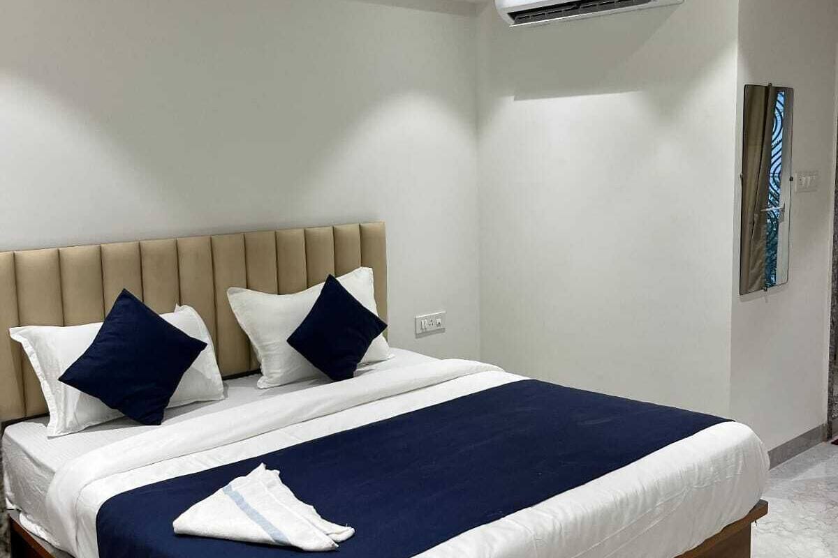 A hotel room with a bed, a ceiling fan, an air conditioning unit, and a window with a view.