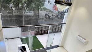 A hotel room with a glass partition, a small desk, and a view of the street outside. - HOTEL MANGALAM REGENCY (Indore)