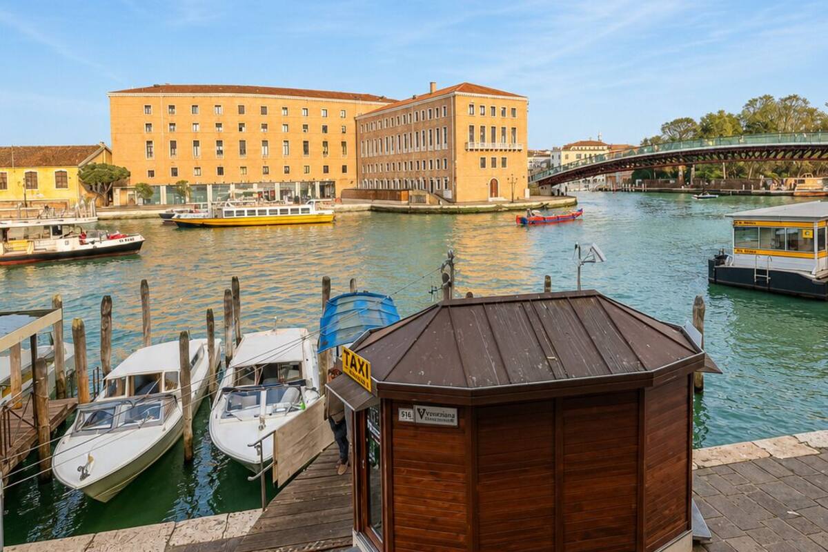 Ein Hotel am Wasser mit einem Steg, Booten und einem großen Gebäude im Hintergrund.