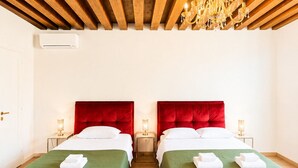 Une chambre d’hôtel avec deux lits, un plafond en bois et un lustre.