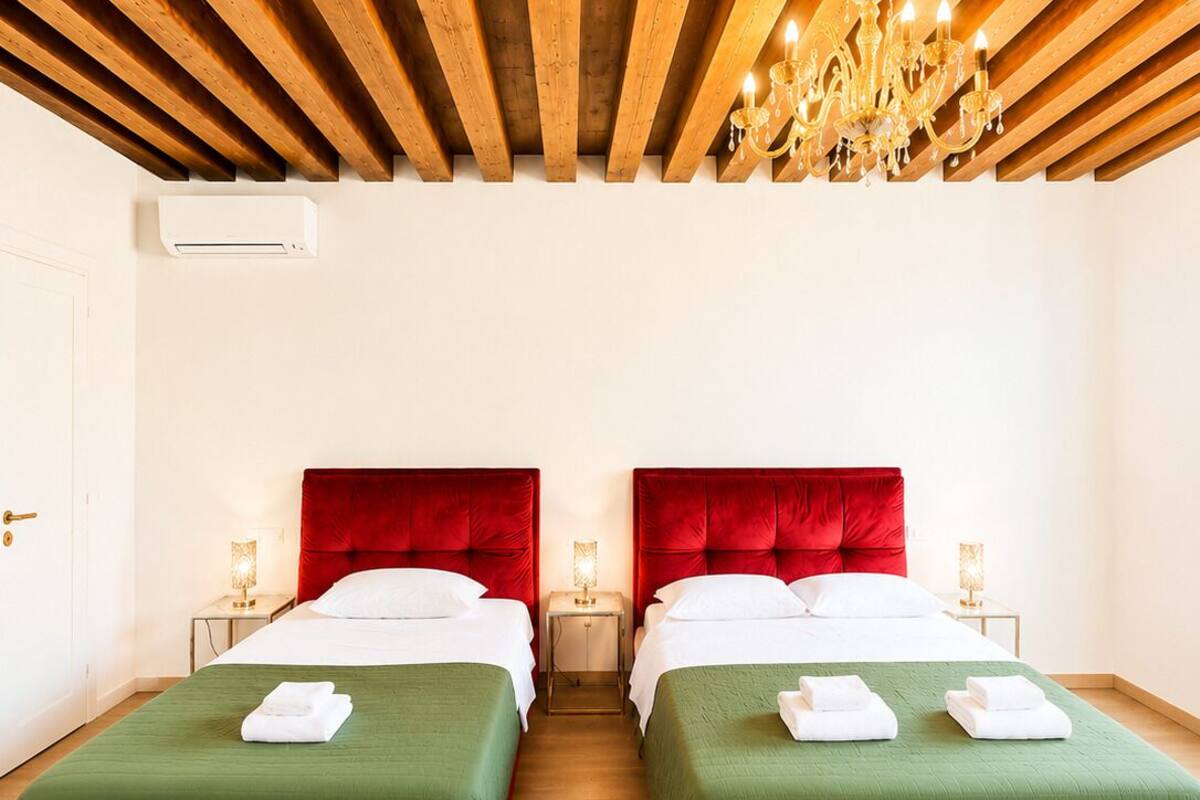 Ein Hotelzimmer mit zwei Betten, einer Holzbalkendecke und einem Kronleuchter.