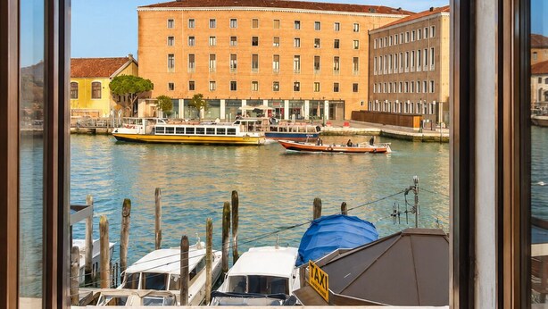 Une vue sur une rivière avec des bateaux, un bâtiment doté de nombreuses fenêtres et un quai avec une zone abritée.