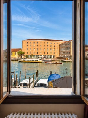 Vista di un fiume con barche, un edificio con numerose finestre e un molo con una zona coperta.