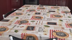 A kitchen with a dining table covered in a tablecloth, a stove, a microwave, and cabinets. - Gîte near Puy du Fou (Montournais)